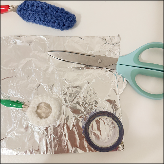 Cutting aluminium foil into the shape of previously crocheted shells.